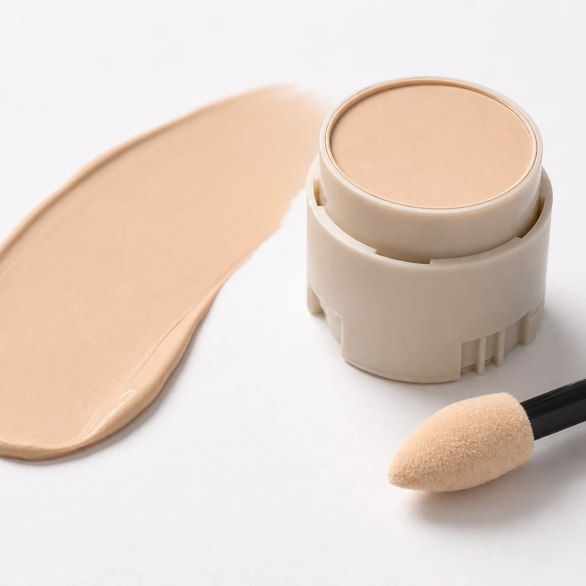 Base makeup stick and blending sponge on neutral surface