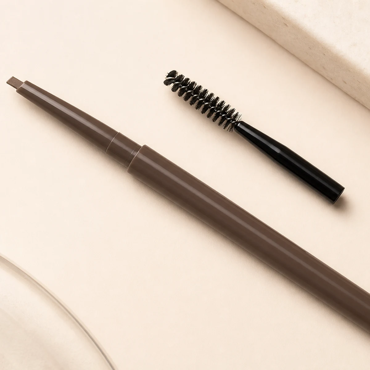 Brow pencil detail and spoolie on a clean workspace